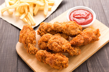 Fried chicken drumstick and french fries on wooden table