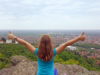 Happy little girl with thumbs up looking at the city