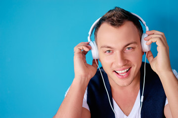 Enjoying the sound. Colorful portrait of happy young man with white earphones is listening music.