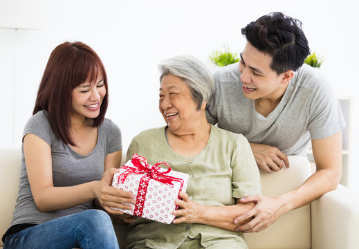 happy  young couple giving  present to grandmother