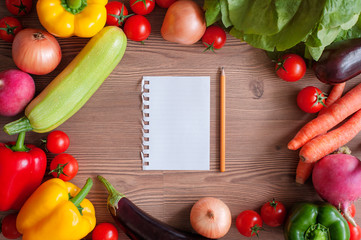 Fresh colorful vegetables and paper for notes and recipes on wooden background. Top view. concept of recipe for healthy meal..