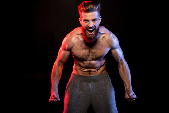 handsome bodybuilder gesturing and yelling isolated on black with dramatic lighting
