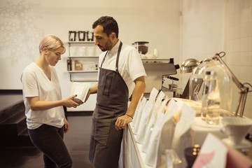 Male and female barista checking packaging of coffee