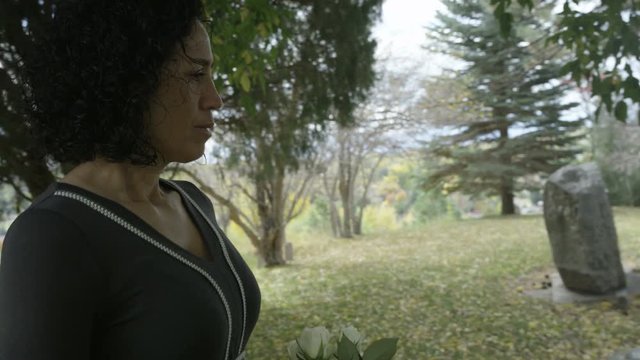 Woman visits gravestone at cemetary