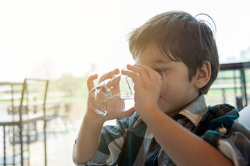 Asian boy drinking water in the room.