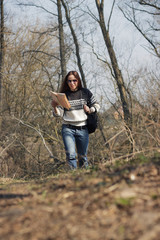 Woman walks in the spring's forest with a map in the hand