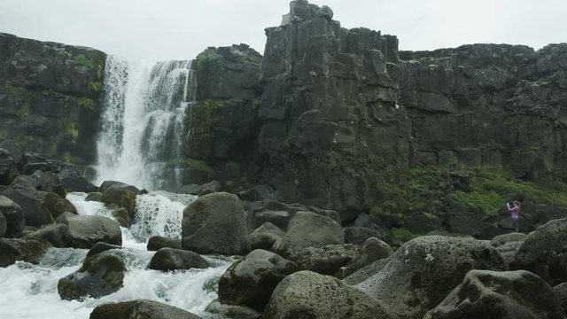 Woman taking picture of waterfall in Iceland