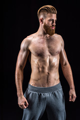 Fototapeta na wymiar handsome bearded sportsman posing and standing isolated on black in studio
