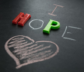 The inscription I hope with chalk and plastic letters on a dark background and a heart