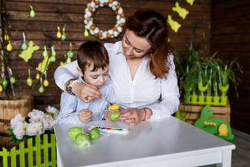 Obraz premium Mother and son are painting eggs. Happy family are preparing for Easter
