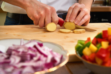 Man's hands cutting fresh tomatos in the kitchen, preparing a meal for lunch. Topdown view.