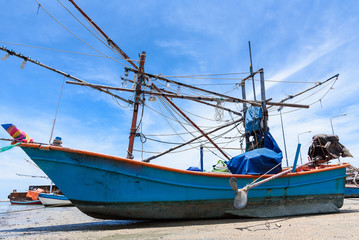 Fishing boats aground on the beach over cloudy sky at Prachuap Khiri Khan, Thailand.