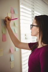 Woman  writing on sticky note by window