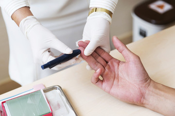 Close up of nurse hands doing blood testing on man's hand