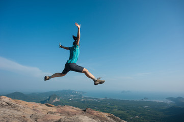 jumping on rocky mountain peak, freedom, risk, challenge, success concept