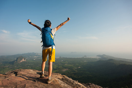 cheering successful woman hiker open arms on mountain top