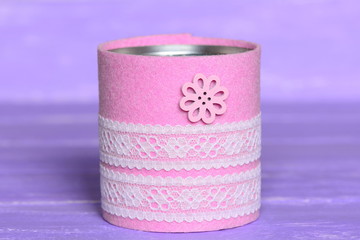 Recycled can isolated on wood background. Tin can decorated with felt, lace and flower button. Inexpensive way to make craft projects for home. Recycling tin can into organizer or planter for kitchen