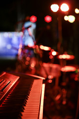 Piano synthesiser on stage with red lighting