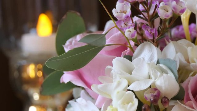 Close up of bouquet of flowers and blurred candle light in the background, loop.