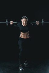 Fototapeta na wymiar young fitness woman training with barbell isolated on black.