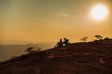 Tourists watching the sunset on top of the mountain.