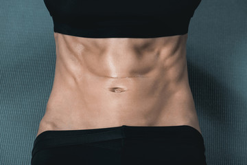 woman's muscular body with abs on mat. sport concept