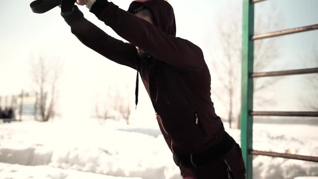 Young caucasian or middle eastern man exercising with fitness straps outdoors