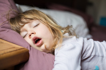 funny face expression with open mouth of blonde caucasian three years old child,  sleeping on king...