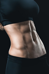 Fototapeta premium woman's muscular body with abs isolated on black. sport concept