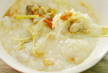 boiled rice with chop pork and slice ginger on plastic soup spoon