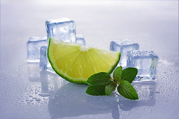 Blue wet ice cube with slice of lime and mint