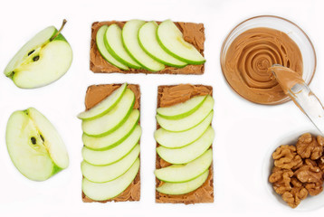 Sandwiches with peanut butter and an apple on the table close-up. Apple slices, walnuts isolated on...