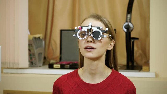 Young blond-haired woman examining her eyesight at the optometrist's. HD