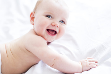 Baby girl in white bedding at home look nice