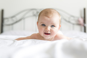 Baby girl in white bedding at home look nice