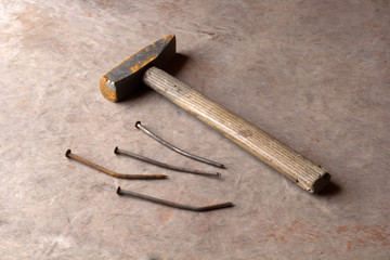 old rusty nails and hammer on a wooden background