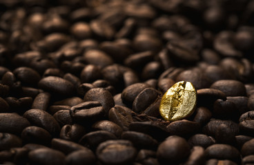 Individuality concept, close up of a single bright, gold coffee bean over many dark ones with copy space