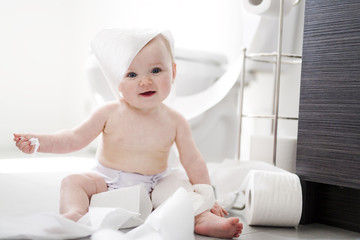 Toddler ripping up toilet paper in bathroom