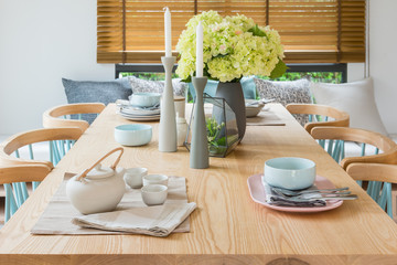 wooden dining table in modern dining room with table set and vase of plants