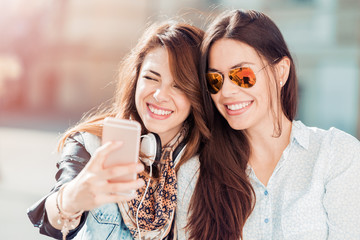 Two woman listening to music and relaxing in the city