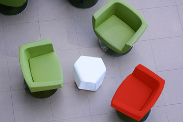 Top view two green chairs and one red with a white table