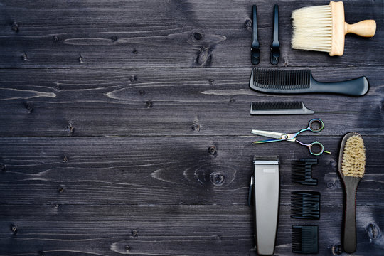 Hairdresser tools on wooden background. Top view on wooden table with scissors, comb, hairbrushes and hairclips, free space. Barbershop