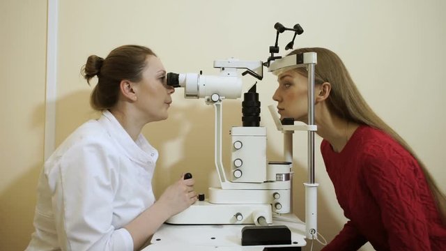 Professional oculist examining and treating eyes of an young attractive woman. HD