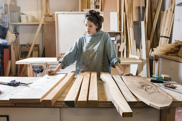 Young woman choosing wood from a selection in a workshop