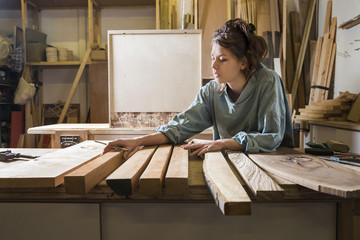 Young woman choosing wood from a selection in a workshop