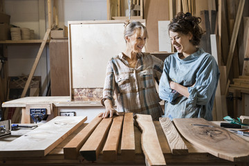 Two women choosing wood from a selection in a workshop