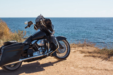 Fototapeta na wymiar Black motorcycle on beautiful seacoast and blue sky onward. Prairie, steppe, summer.