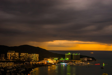 Fototapeta premium Sunset view of Sanya corner with city lights. View from Luhuitou Park on Hainan Island of China.
