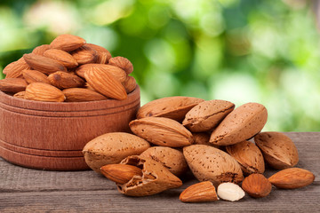 almonds in a bowl on the old wooden board with blurred garden background