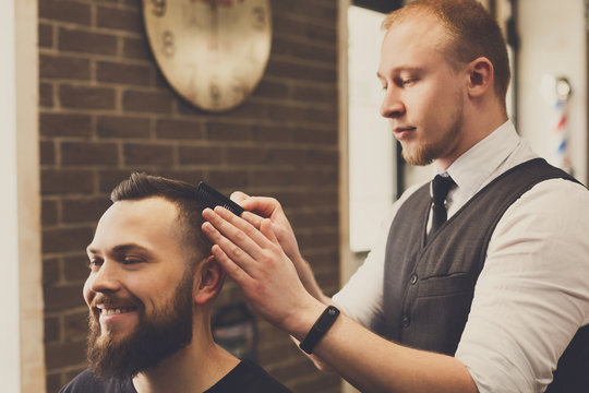 Man getting haircut by hairstylist at barbershop